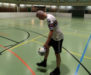 Ein Mann jongliert mit einem Fußball.