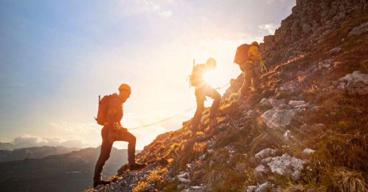 Drei Bersteiger wandern in einer Seilschaft auf den Berg.