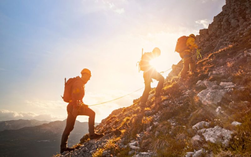Drei Bersteiger wandern in einer Seilschaft auf den Berg.