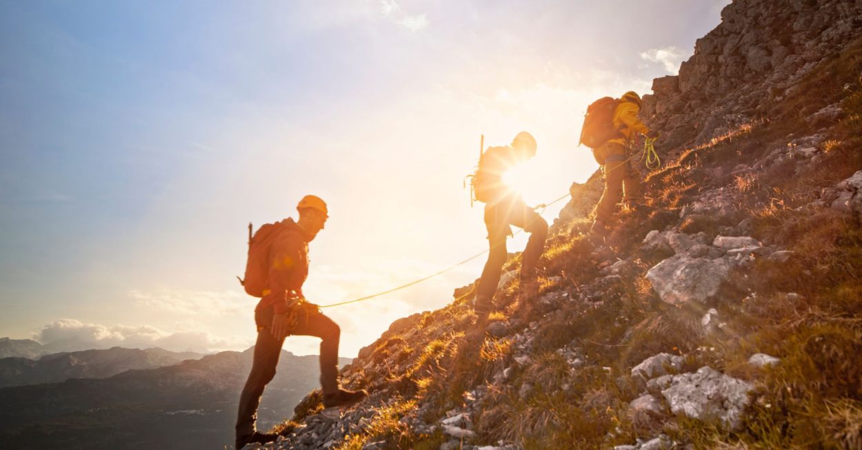 Drei Bersteiger wandern in einer Seilschaft auf den Berg.