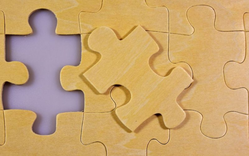 Das Bild zeigt ein Puzzlestück, das in ein Gesamtpuzzlebild passt. Es symbolisiert, dass etwas zusammenpasst.