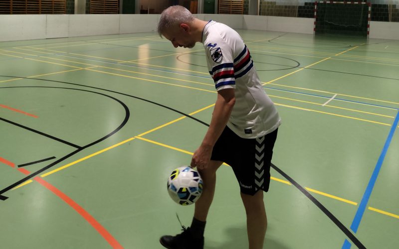 Ein Mann jongliert mit einem Fußball.