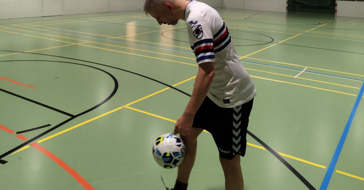 Ein Mann jongliert mit einem Fußball.